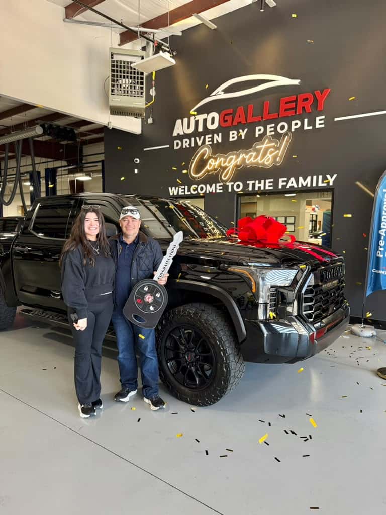 Customers celebrating a Toyota pickup delivery at Auto Gallery