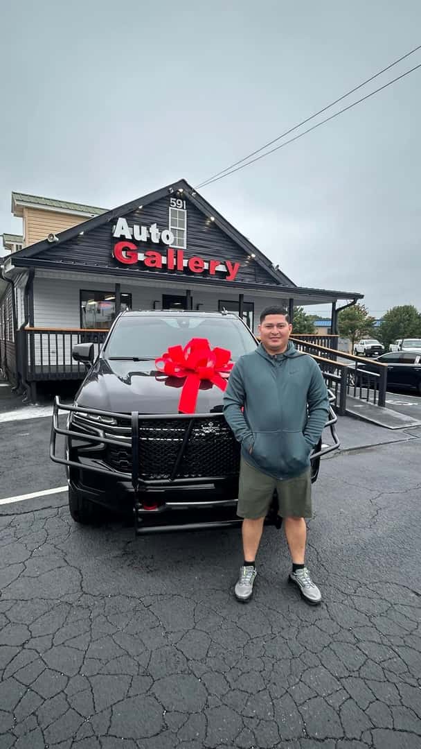 Customer beside an SUV with a red bow outside Auto Gallery