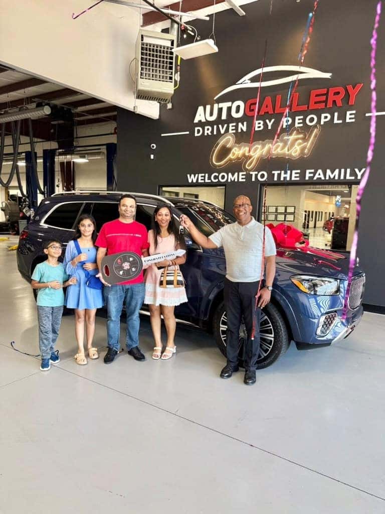 A family and team member celebrating a vehicle delivery inside Auto Gallery