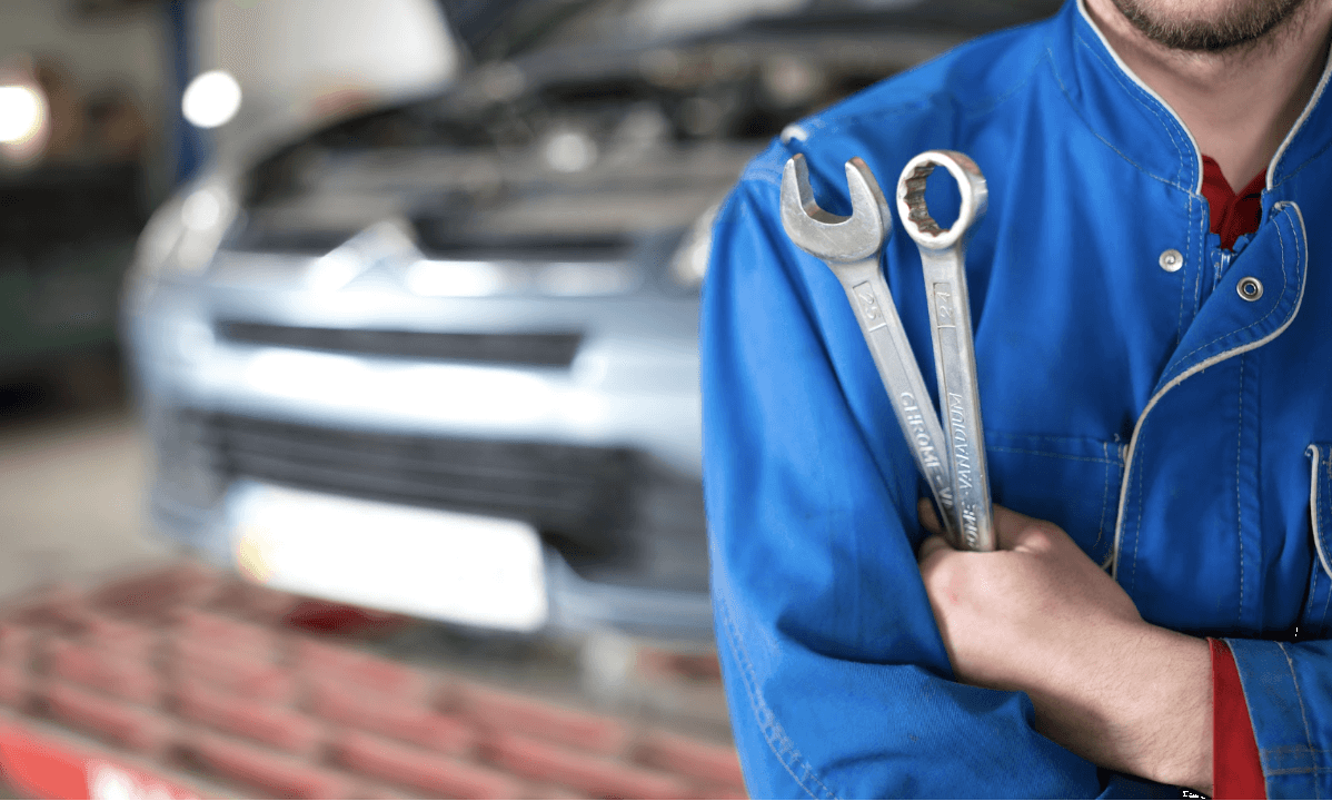 Man holding car wrenches in front of a sedan
