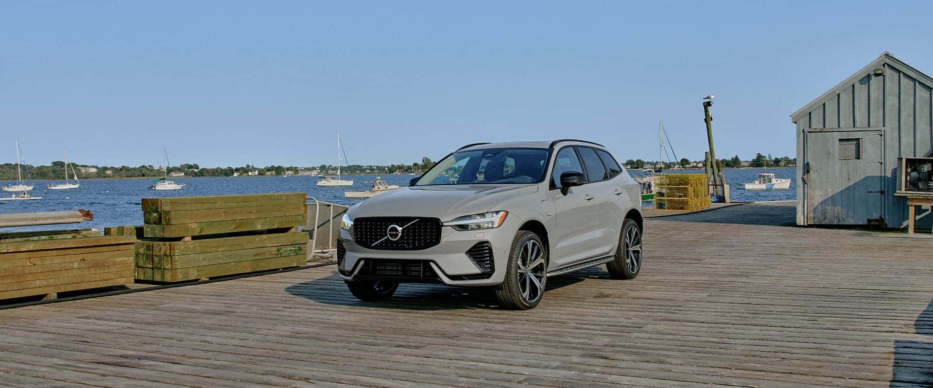 2026 Volvo XC60 | Gray Volvo XC60 Parked on Dock Next to Lake With Boats Sailing in the Background