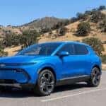 2026 Chevrolet Equinox EV plugged into a DC fast charger with Sierra Nevada foothills in the background