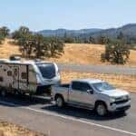 2026 Chevrolet Silverado 1500 pulling a travel trailer on the I-80 Sierra Nevada foothills grade east of Auburn, California in summer