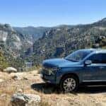 2026 Chevrolet Suburban parked at a Sierra Nevada foothills canyon overlook with rear liftgate open and summer gear loaded