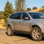 Used Chevrolet Traverse on an Auburn, CA foothills road with pine trees in the background