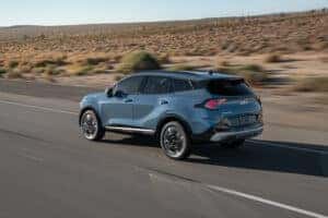 side and back of blue 2026 Kia Sportage driving on road