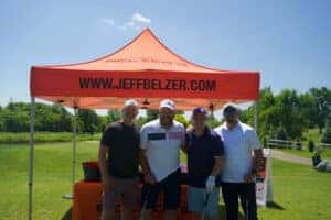 Four man standing together in front of Jeff Belzer tent 