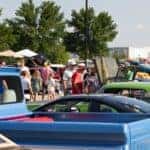 Blue truck, green car, and people looking at cars in the background