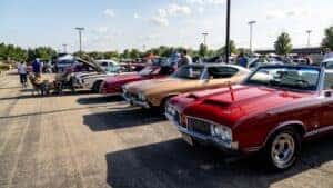 red car, beige car, red car, and white car at car show 
