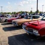 Red car, beige car, red car, and cream car at car show