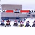 snowmobiles lined up at starting line of Snocross event