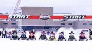 snowmobiles lined up at starting line of Snocross event
