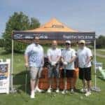 group of golfers in front of Jeff Belzer's tent