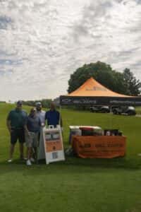 group of golfers standing beside Jeff Belzer's tent at golf tournament