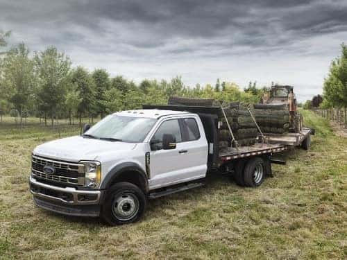 2024 RAM Chassis Cab towing two trailers of lumber and a tractor