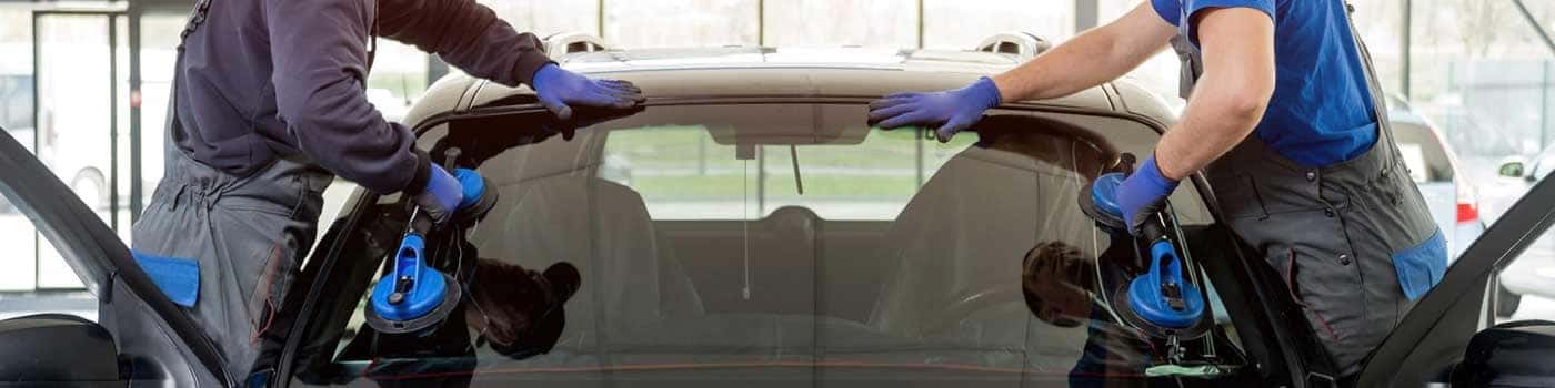 Close up view of two service techs replacing the wiper blades off a vehicle