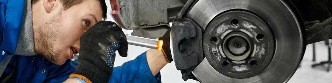View of a service tech inspecting a vehicle's brake pads
