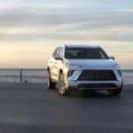 Front and side view of the 2025 Buick Enclave driving through city