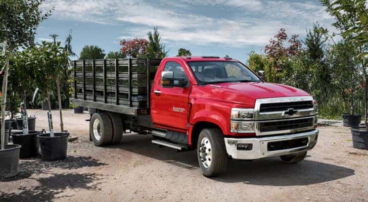 A red 2024 Chevy Silverado 5500 HD parked at a plant nursery.