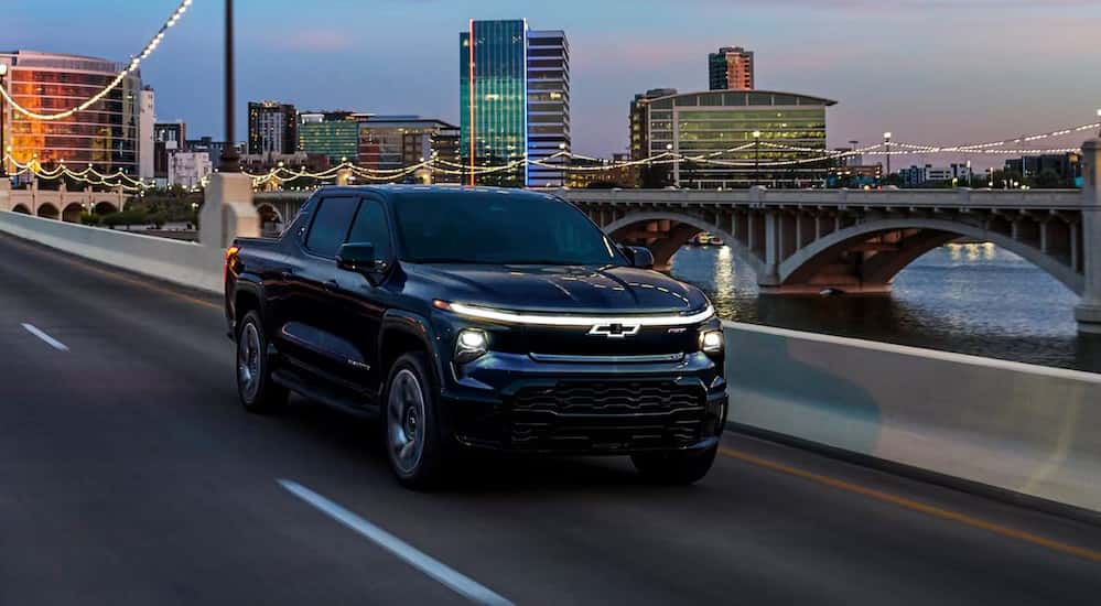 A black 2025 Chevy Silverado EV RST is shown driving on a bridge.