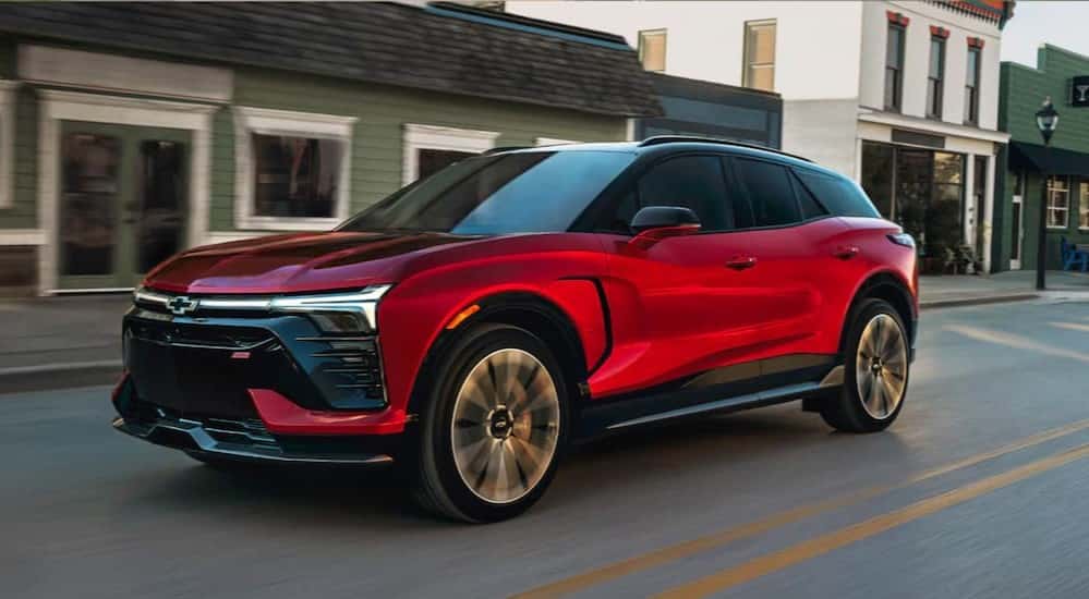 A red 2025 Chevy Blazer EV RS is shown driving in a city.