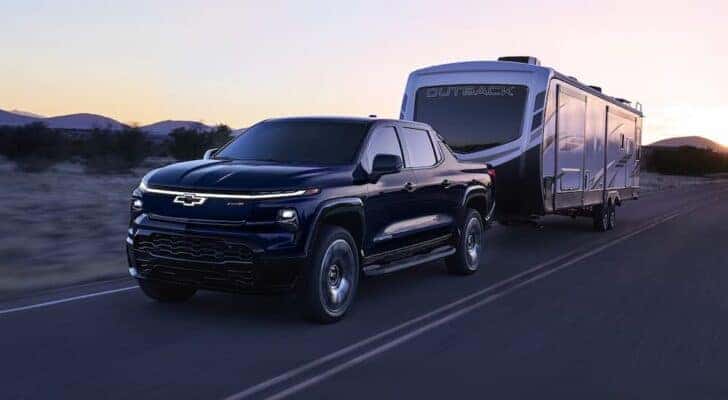 A black 2024 Chevy Silverado EV RST towing a camper.