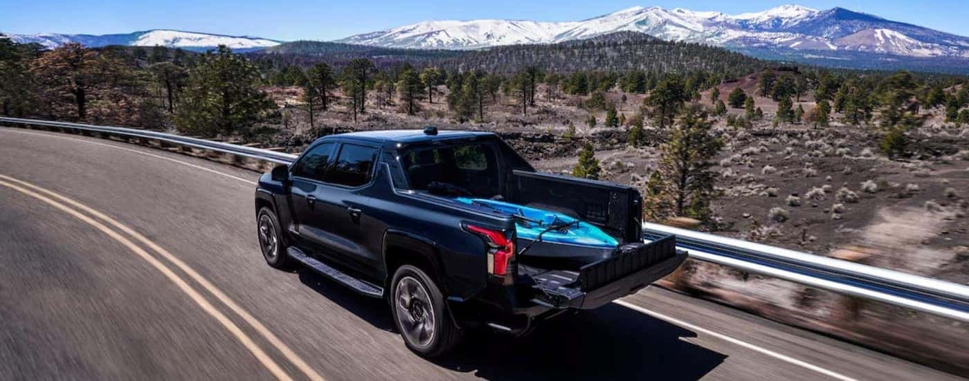 A black 2024 Chevy Silverado EV for sale near Clemmons is shown driving on a highway.
