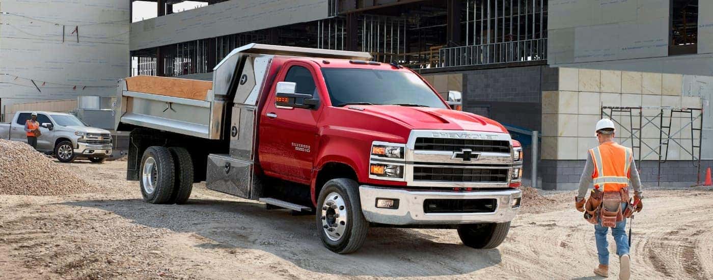 A red 2025 Chevy Silverado 5500 HD parked by a construction site.