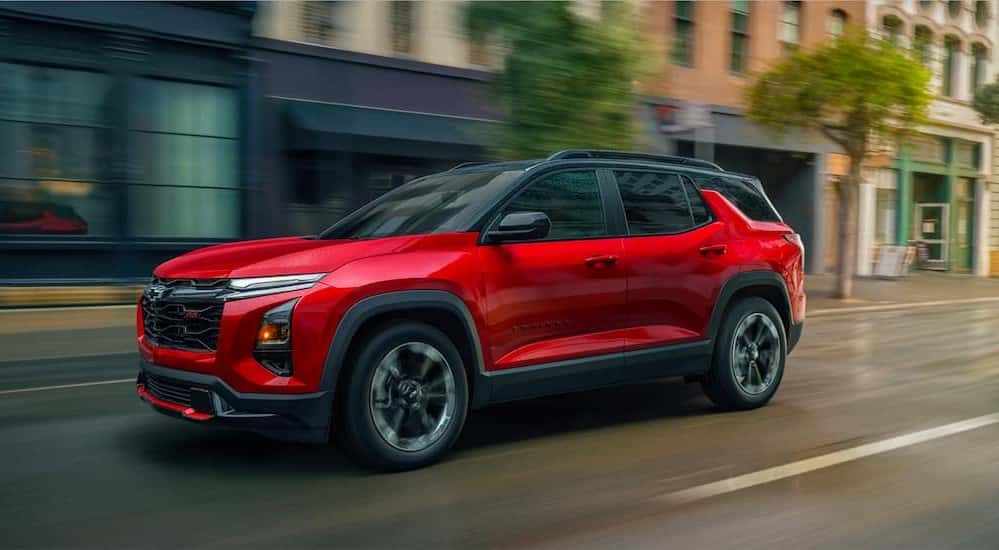 A red 2026 Chevy Equinox RS for sale driving in a city.