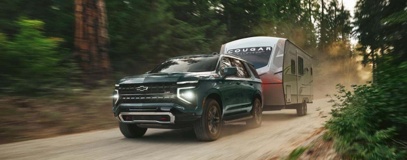 A green 2025 Chevy Tahoe Z71 towing a trailer.