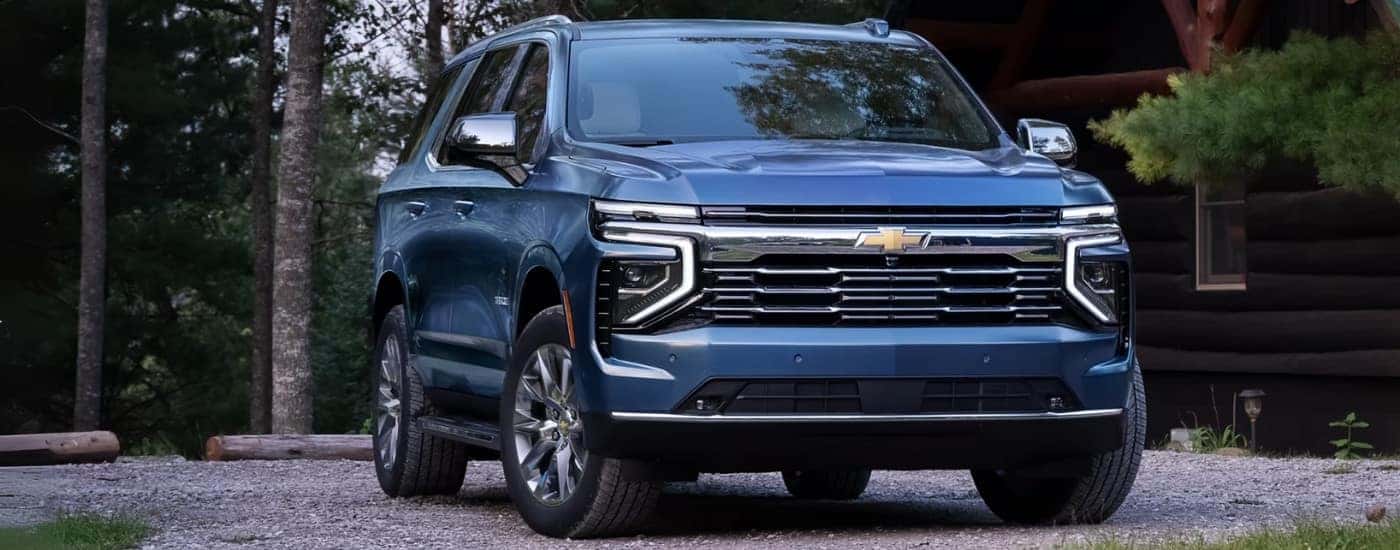 A blue 2025 Chevy Tahoe for sale in Kernersville parked in front of a cabin.