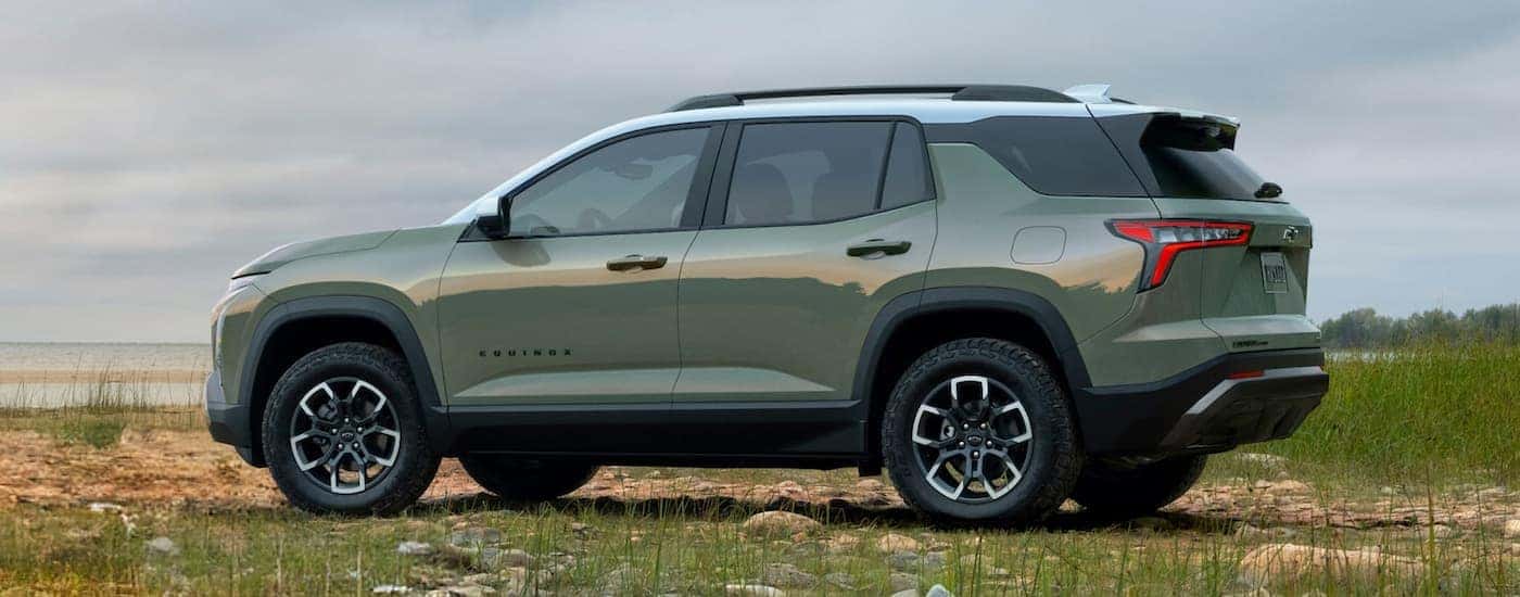 Green 2026 Chevy Equinox ACTIV parked off-road near a lake.