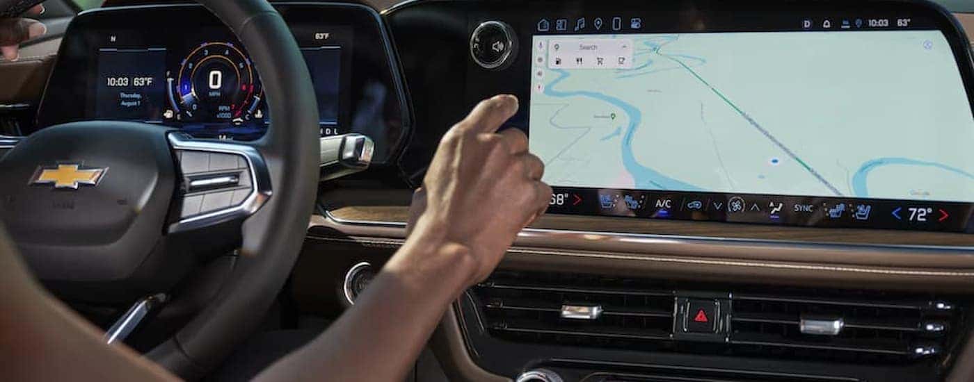 A woman using an infotainment display in a 2025 Chevy Tahoe for sale near Advance