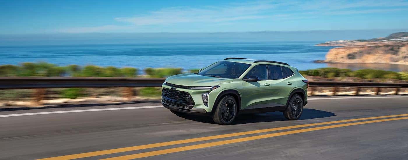 A green 2025 Chevy Trax driving down a highway for sale near Mocksville