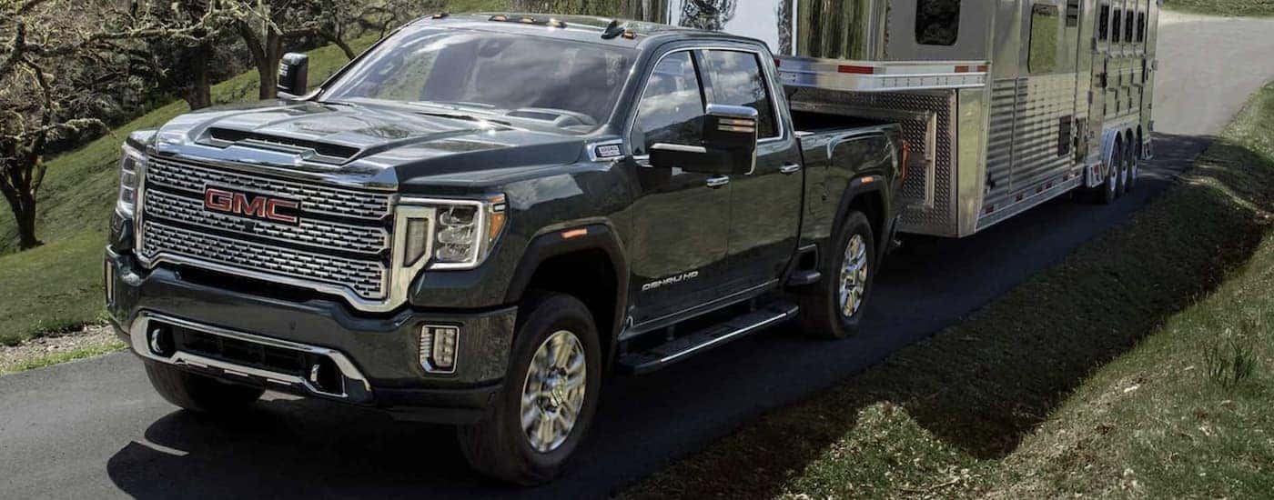 Black 2023 GMC Sierra 3500 HD towing a trailer from a dealer with commercial vehicles for sale.
