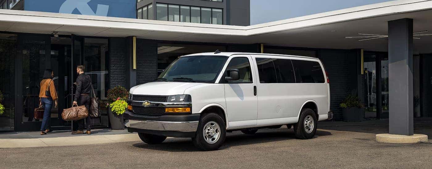 White 2025 Chevy Express Cargo Van parked outside a building.