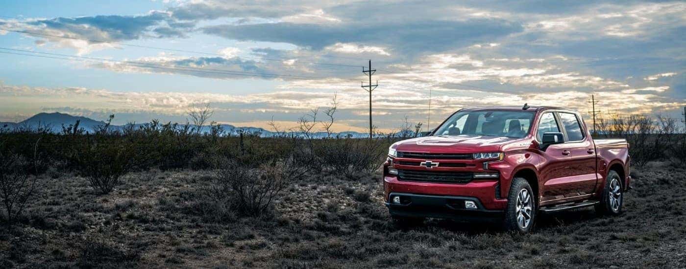 A red 2023 Chevy Silverado 1500 parked near a field.