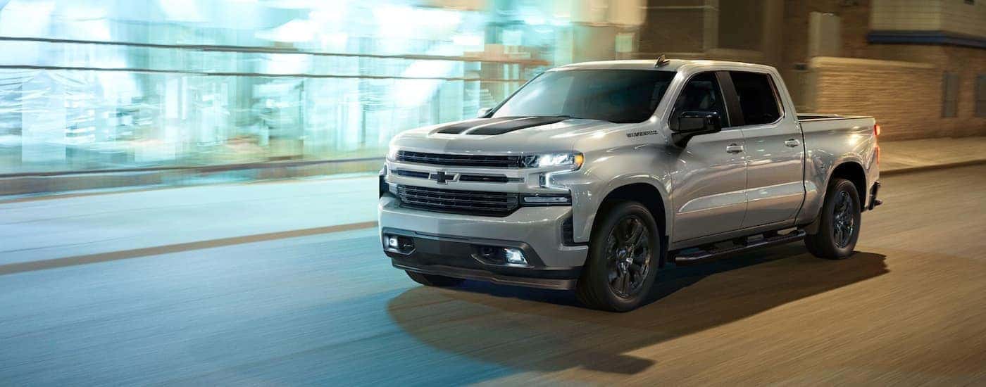 A silver 2023 Chevy Silverado 1500 RST driving in a city.