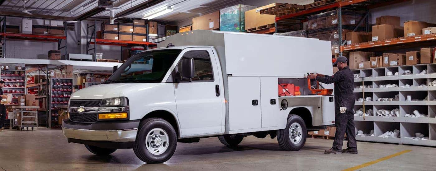 A man using a storage compartment in a 2025 Chevy Express 3500 Cutaway