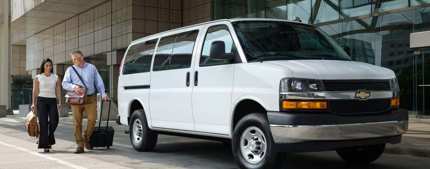 A white 2026 Chevy Express Passenger Van parked outside a building