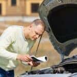 Man trying to jump-start car using Mazda service manual