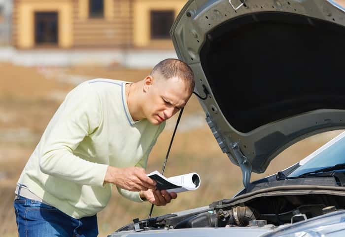 Man trying to jump-start car using Mazda service manual