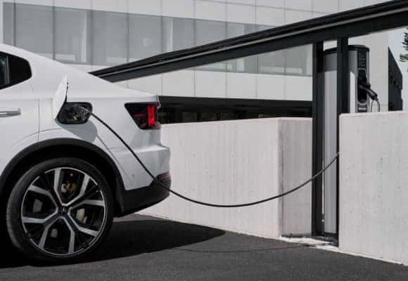 white electric sedan plugged into charger